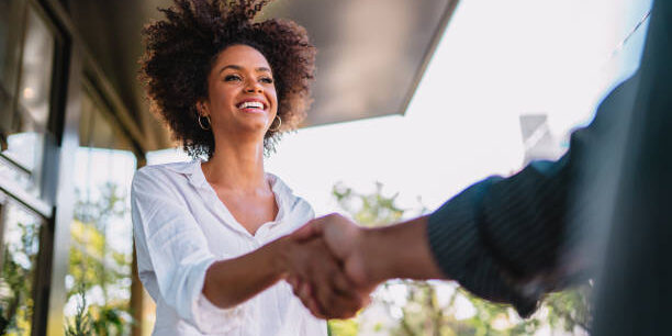 Businessman and woman shake hands like hello in office closeup.